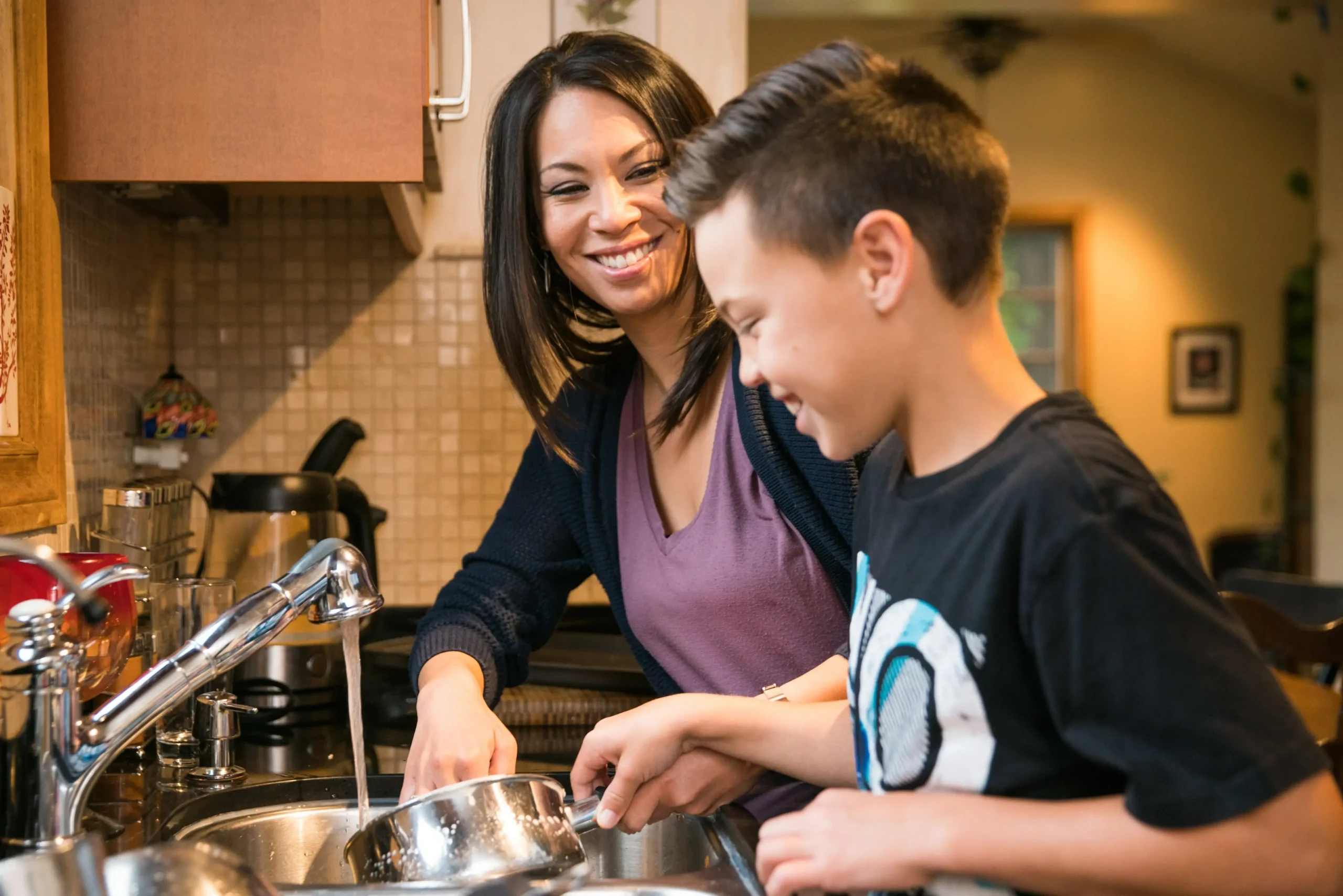 mom and son sharing a laugh while washing dishes