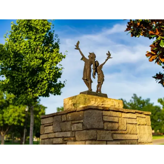 Statue of children and birds on stone pedestal.