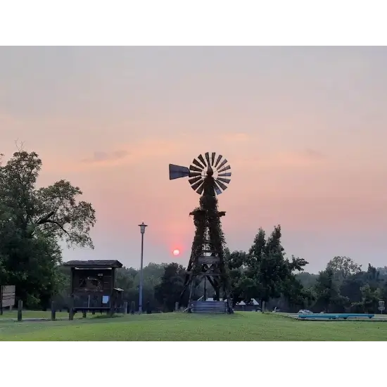 Vintage windmill at sunset in grassy field at choctaw creek park in choctaw, ok. photo by vintage speedwerks
