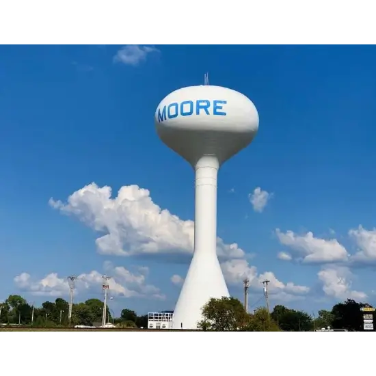 Moore, OK water tower against blue sky and clouds.