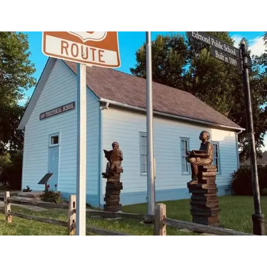 Historic Edmond schoolhouse with statues outside.