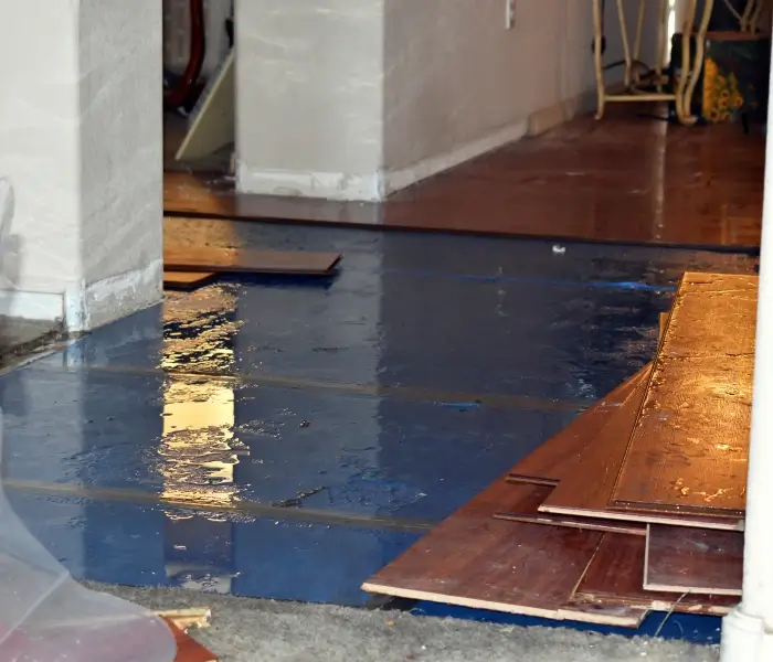 Flooded room with damaged wooden flooring.