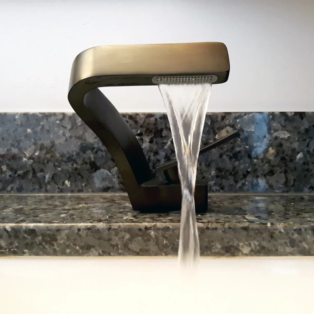 Modern faucet with running water on granite countertop.