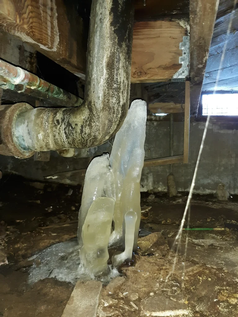 Frozen icicles beneath a leaky metal pipe