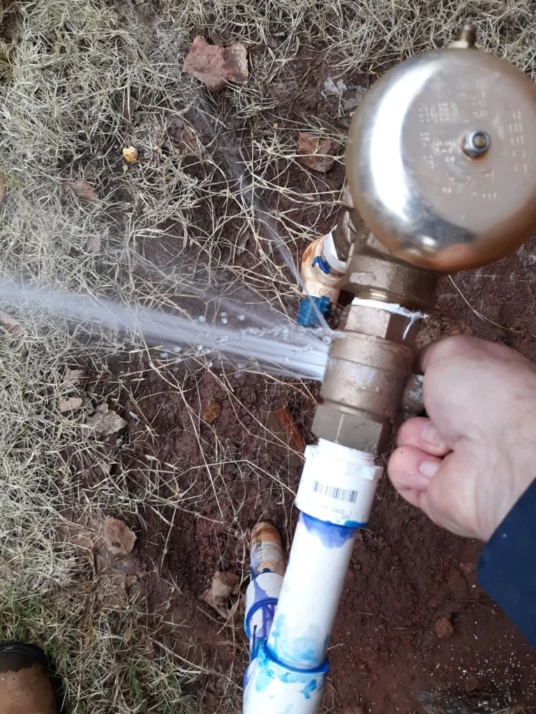Person checking water pressure gauge outdoors.