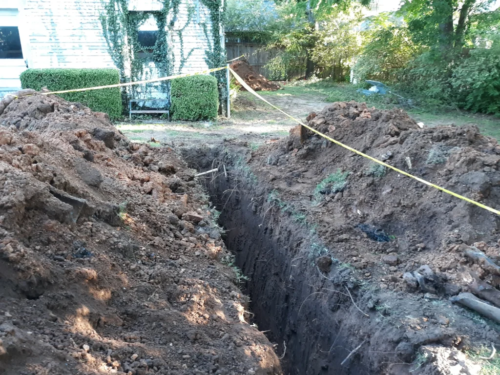 Excavated trench in backyard with caution tape.