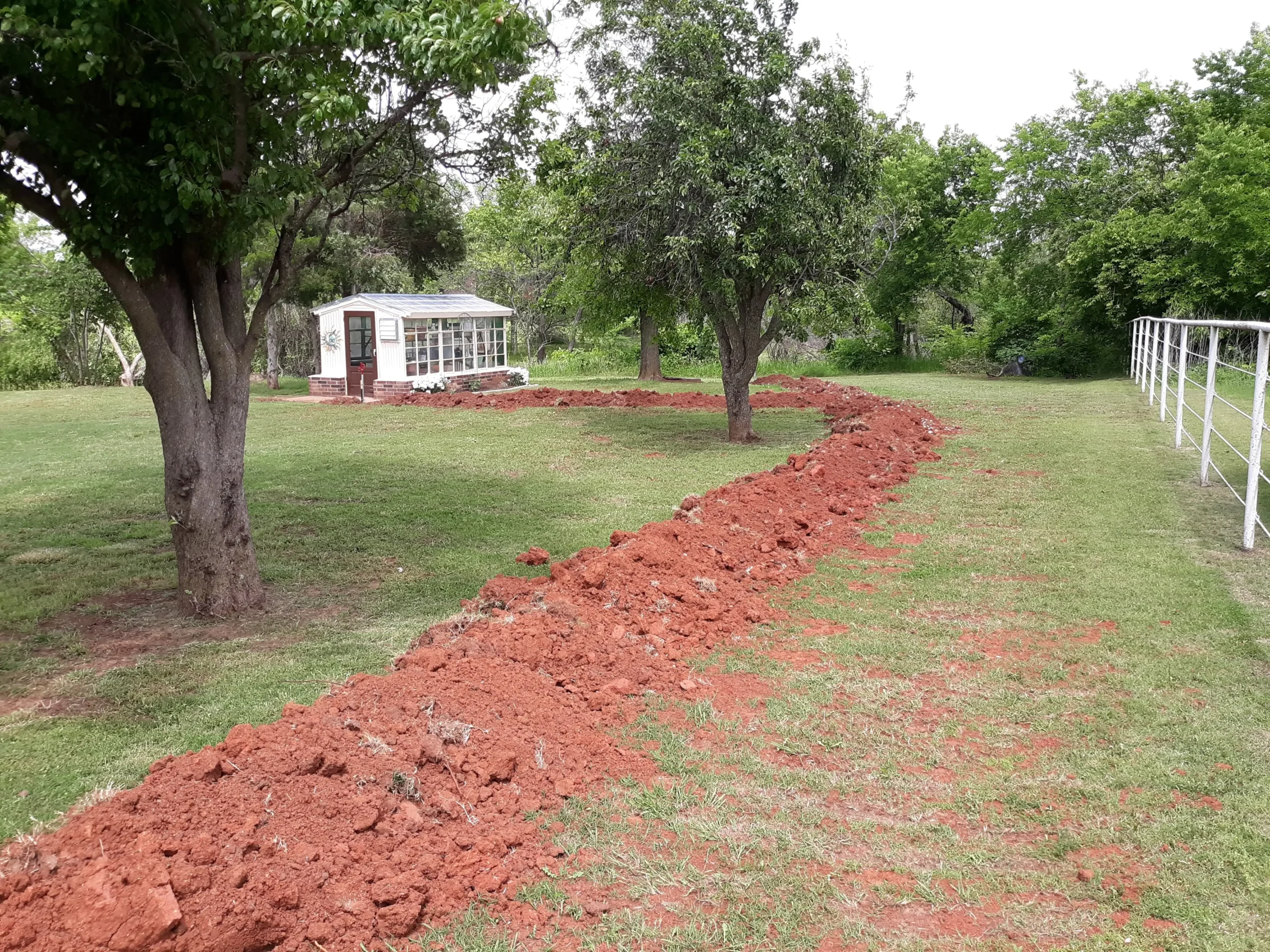800x600 Dug trench near greenhouse and trees in garden.