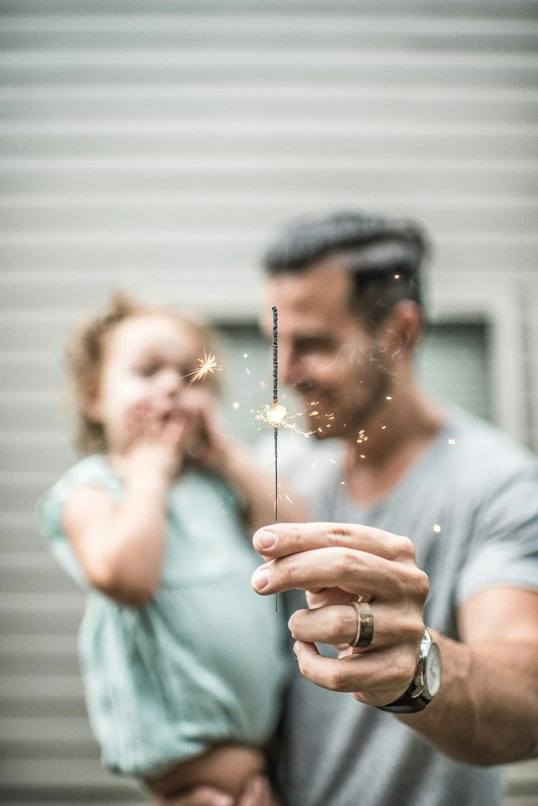 800x1080 Smiling man and child holding a sparkler. photo by caleb jones